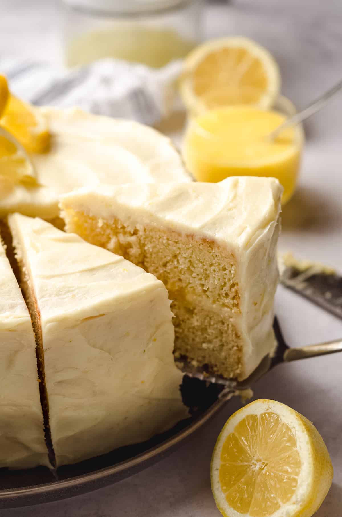 Removing a slice of lemon cake from an intact cake.