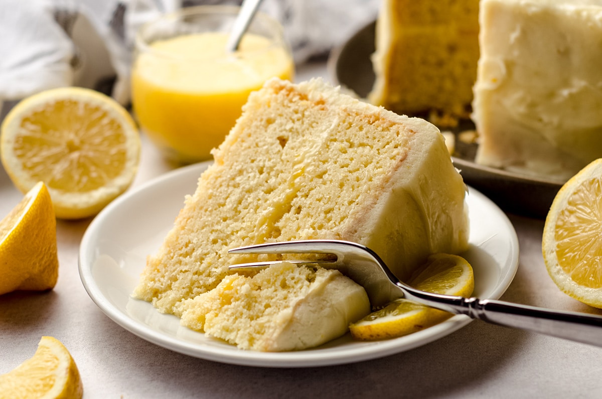 A slice of lemon cake with lemon curd filling with a fork taking a portion out.