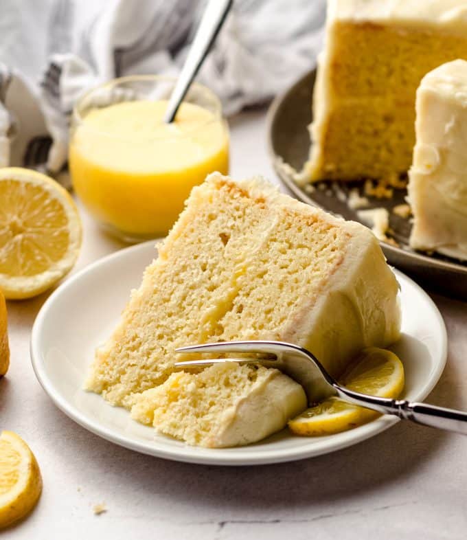 A large slice of lemon layer cake, with a fork taking a portion out.