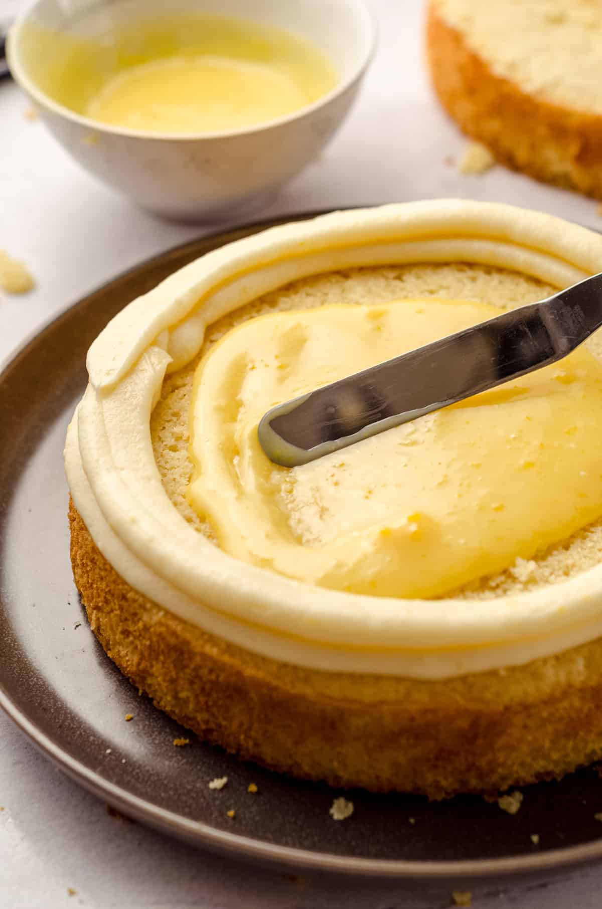 Smoothing lemon curd into the center of a lemon cake.