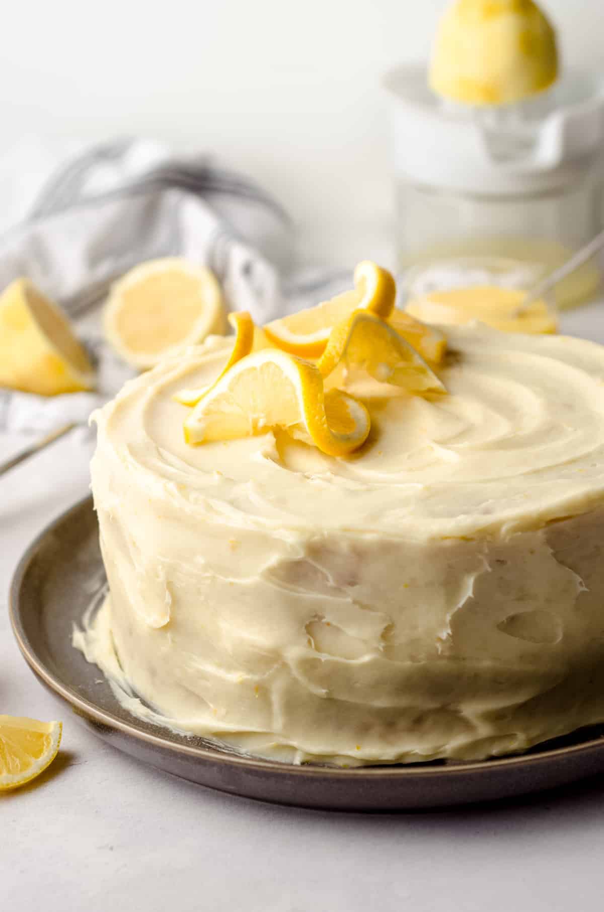 A lemon cake, topped with lemon frosting and lemon slices.