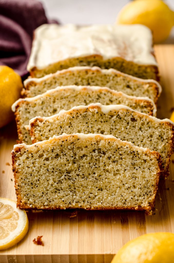 A sliced lemon poppy seed loaf on a wooden cutting board.