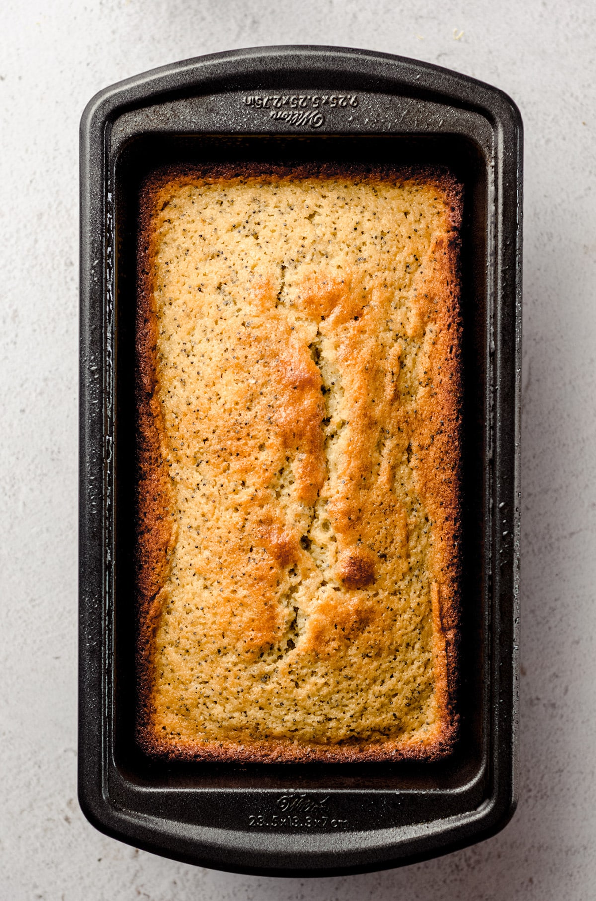 A fully baked lemon poppy seed loaf in a loaf pan.
