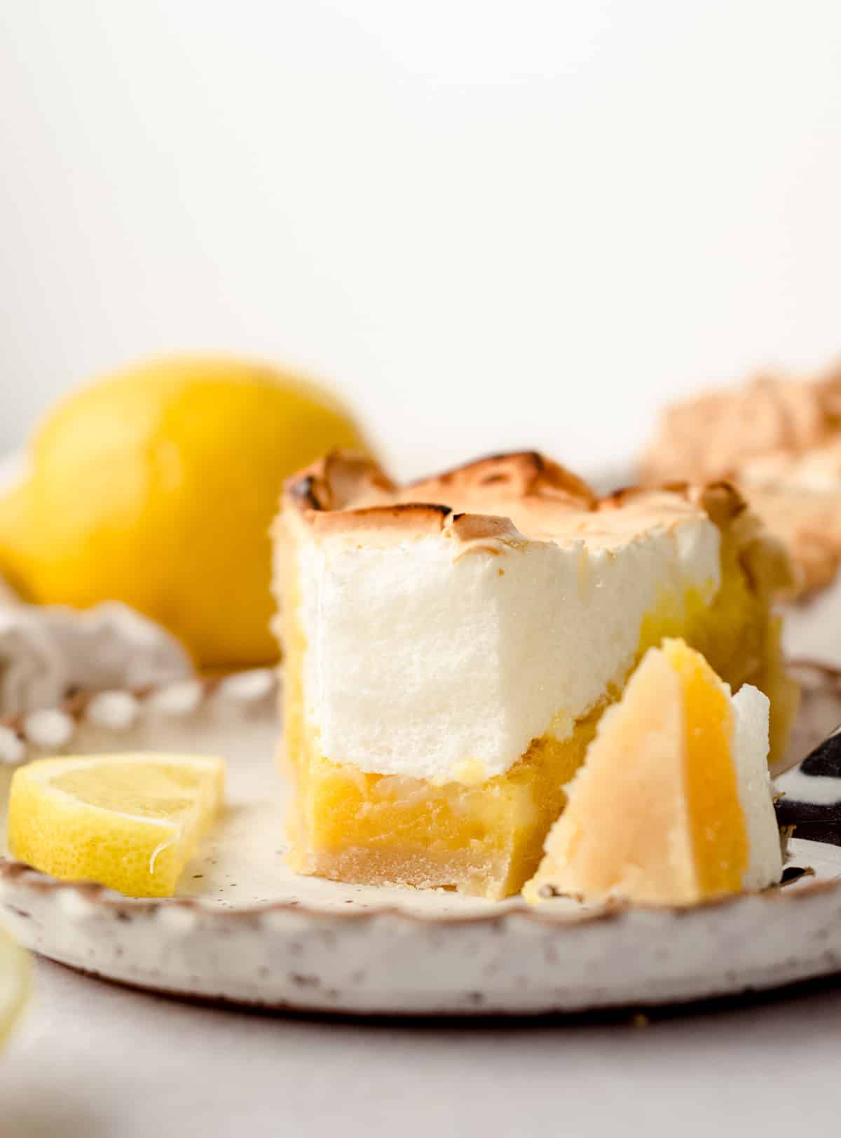 A slice of lemon meringue pie with a forkful taken out.