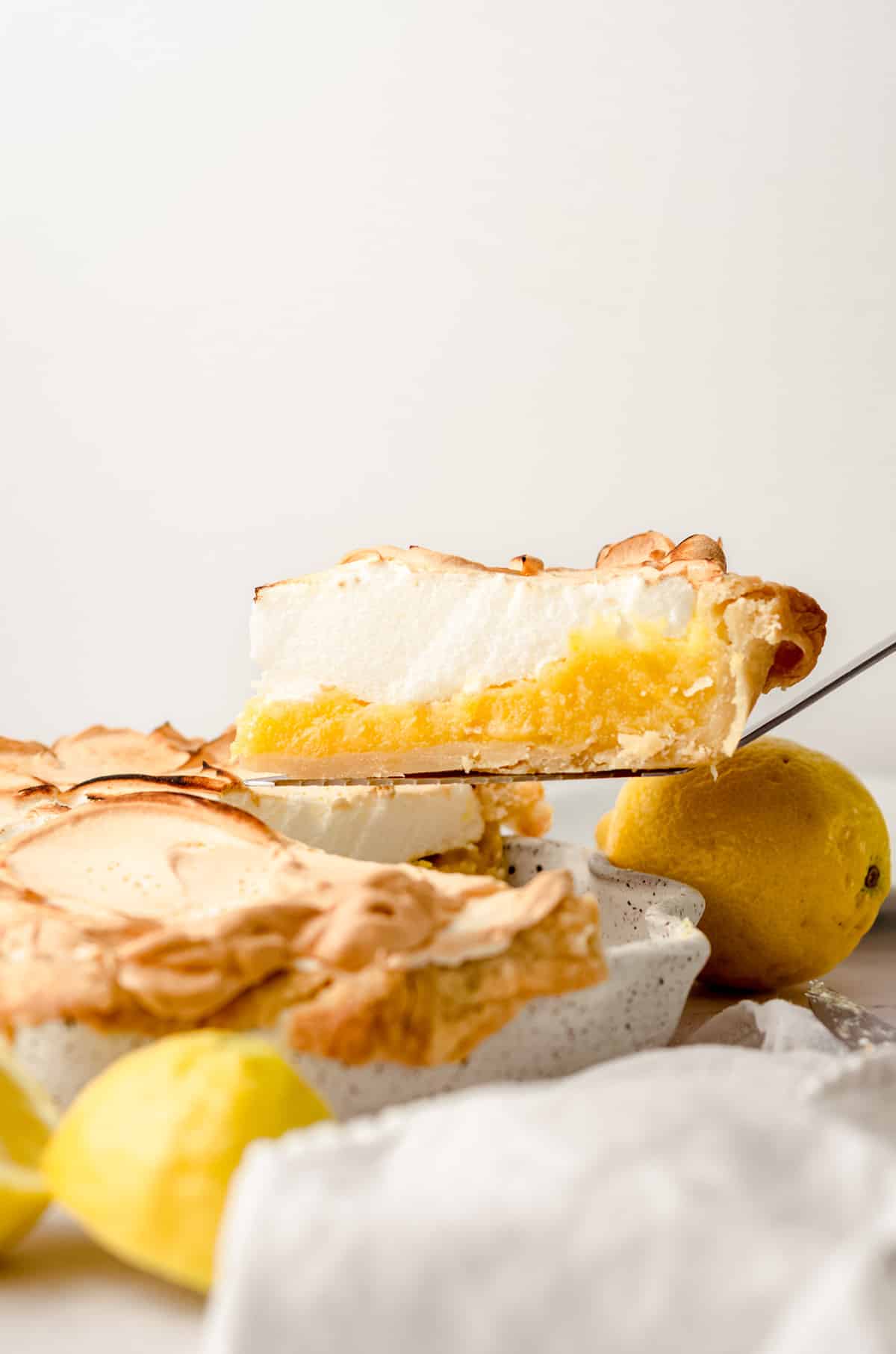A slice of lemon meringue pie being lifted out of a pie plate.