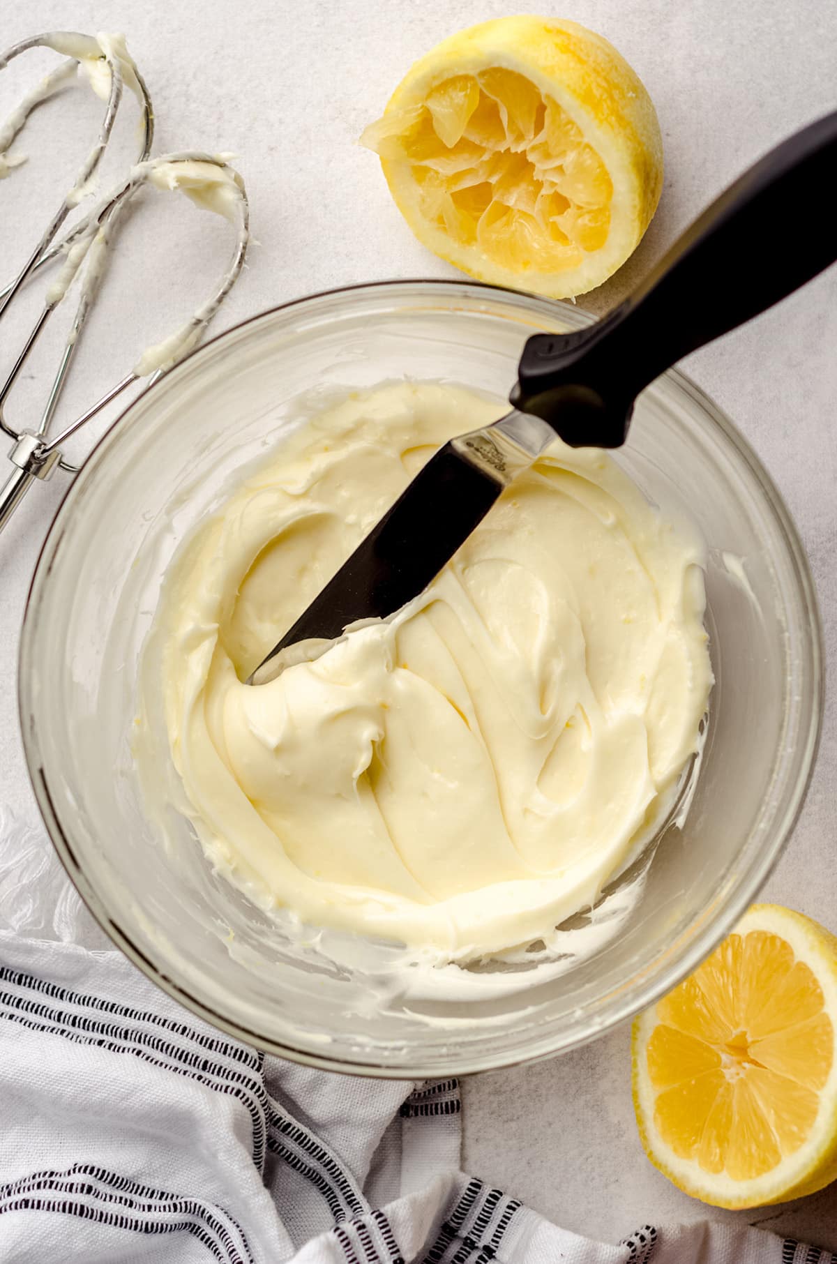 A bowl of lemon cream cheese frosting with an offset spatula inside of the bowl.