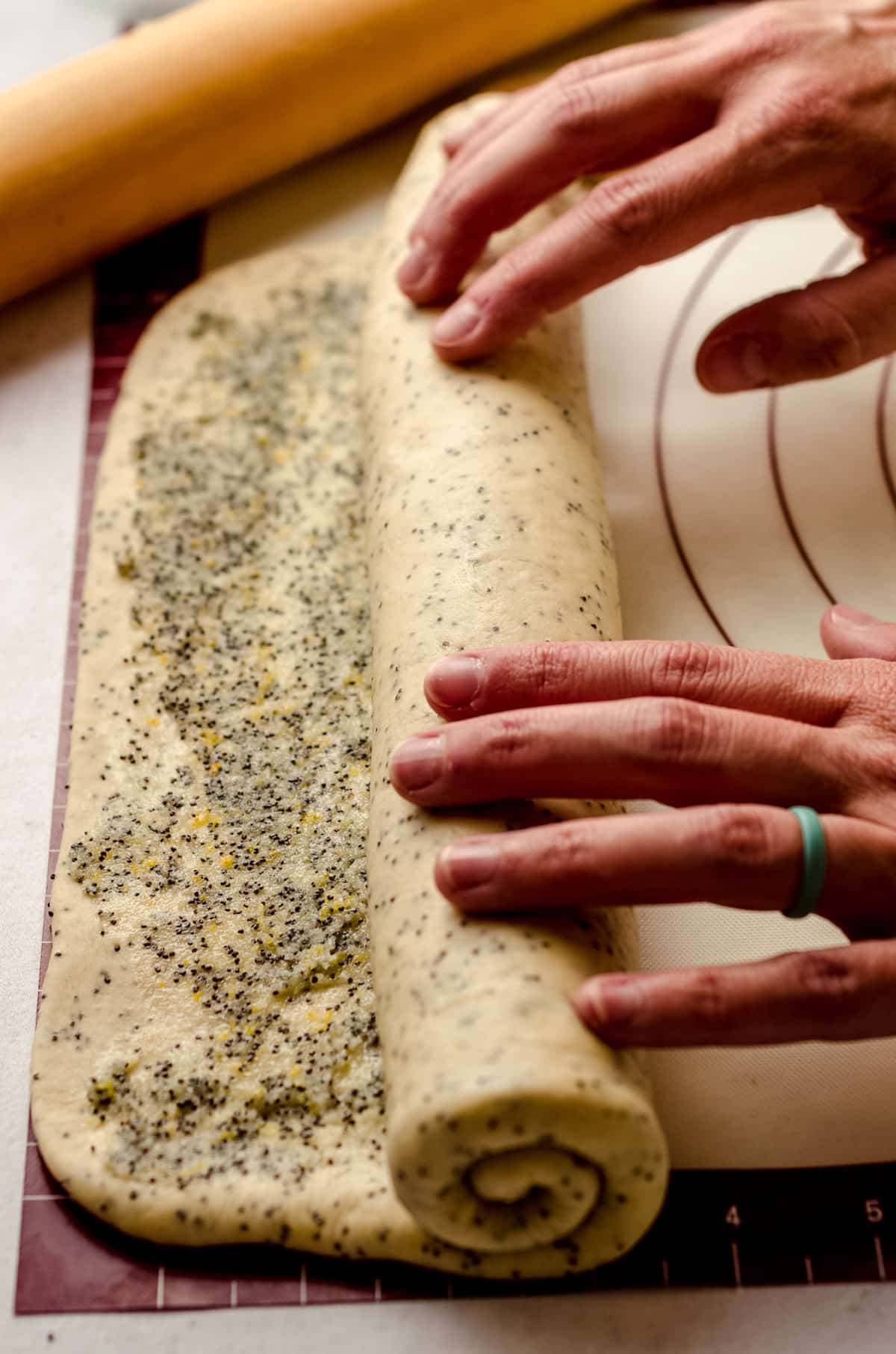 Rolling a lemon poppy seed dough into a log.