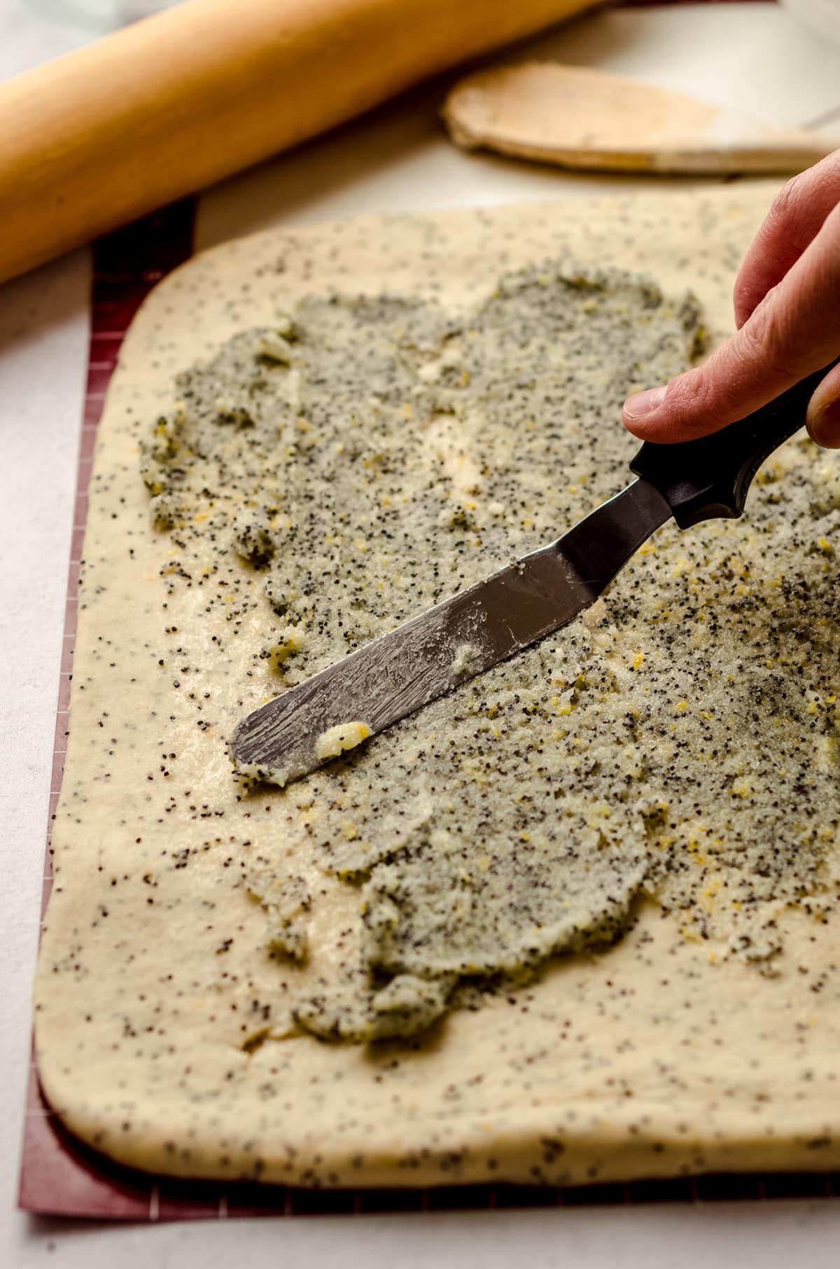 Spreading a lemon poppy seed filling over a sweet dough that has been rolled into a rectangle.