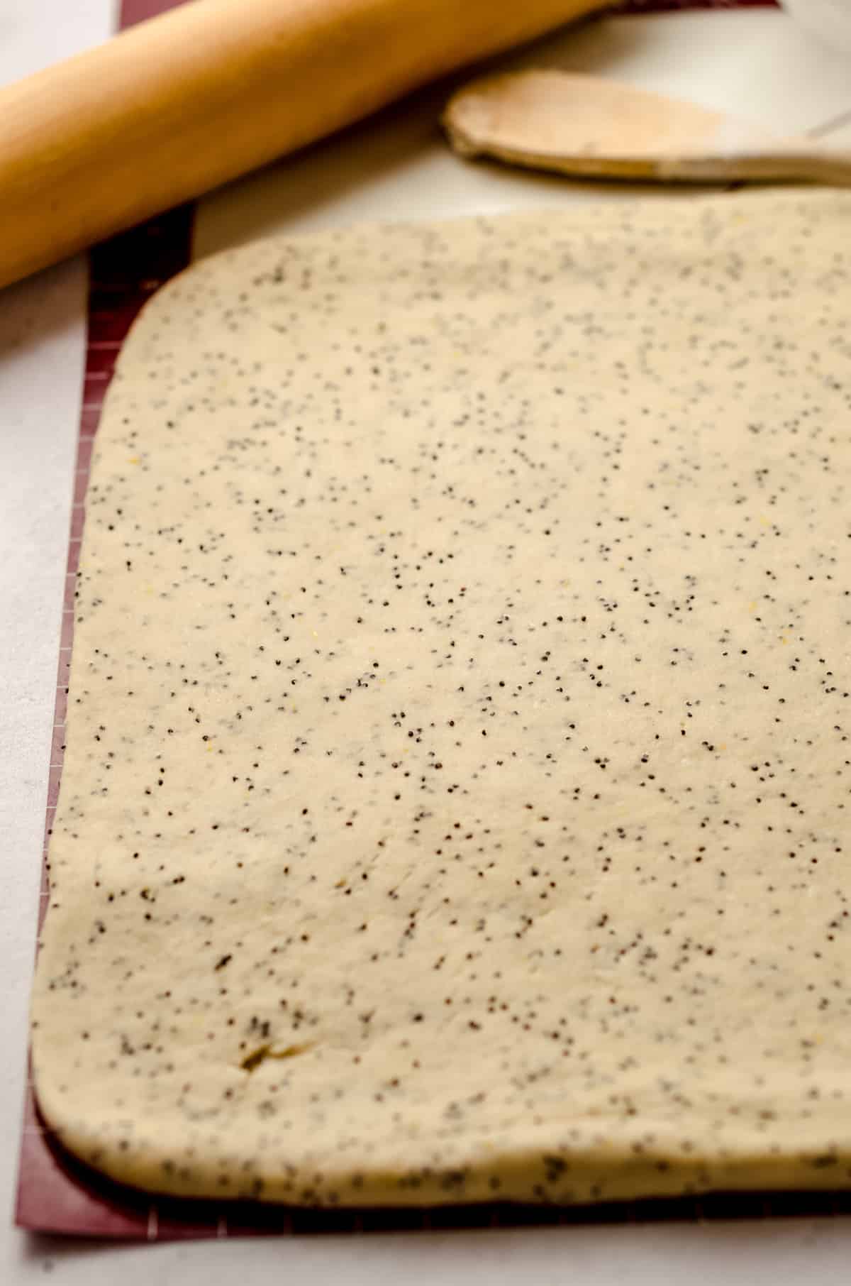 Rolling a lemon poppy seed dough into a large rectangle.