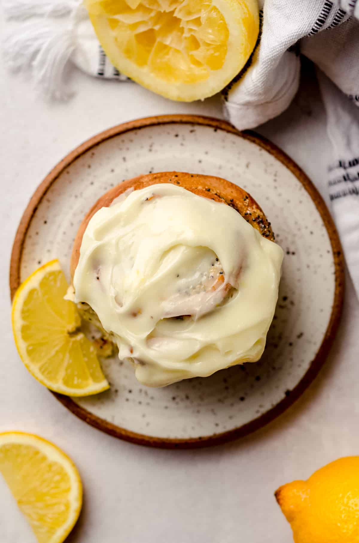 An overhead shot of a lemon poppy seed roll covered with cream cheese frosting.