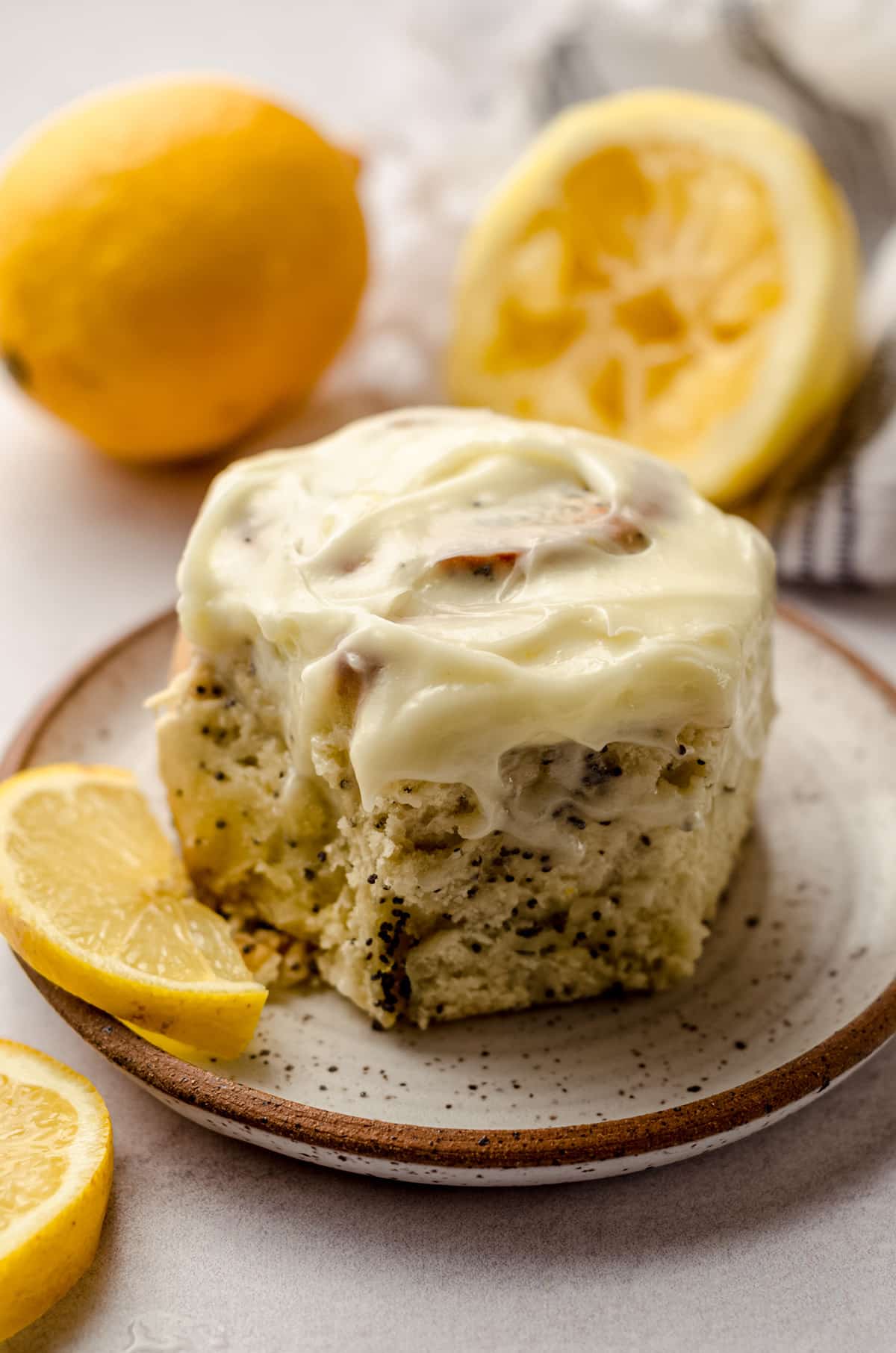 A lemon poppy seed roll on a plate, spread with lemon cream cheese frosting.