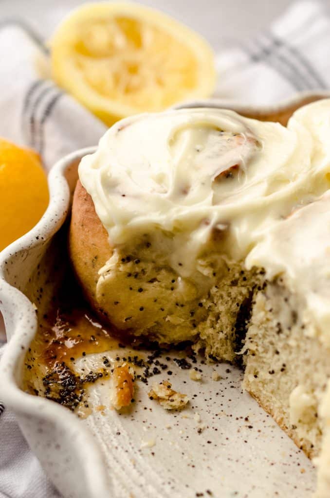 A close up of a pan of lemon poppy seed rolls with cream cheese frosting.