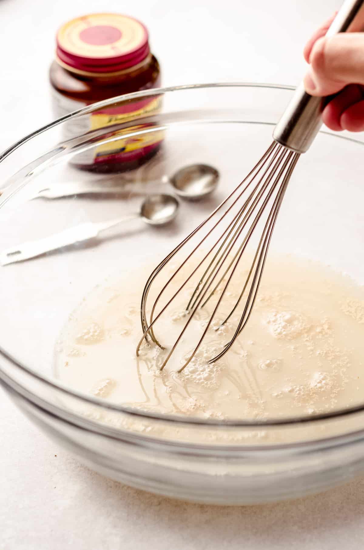 whisking together yeast, water, and sugar to make homemade pizza dough