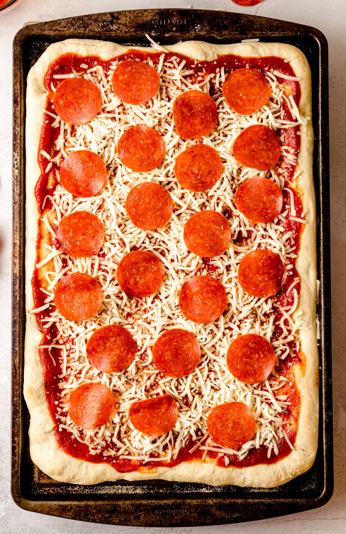 A rectangular pizza made in a sheet pan and topped with pepperoni.