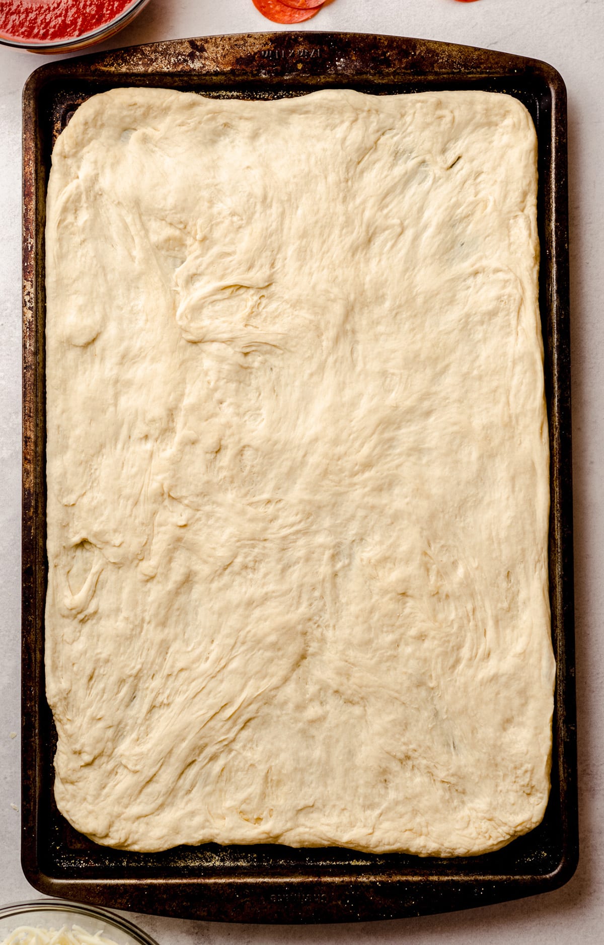 A sheet pan fitted with homemade pizza dough.