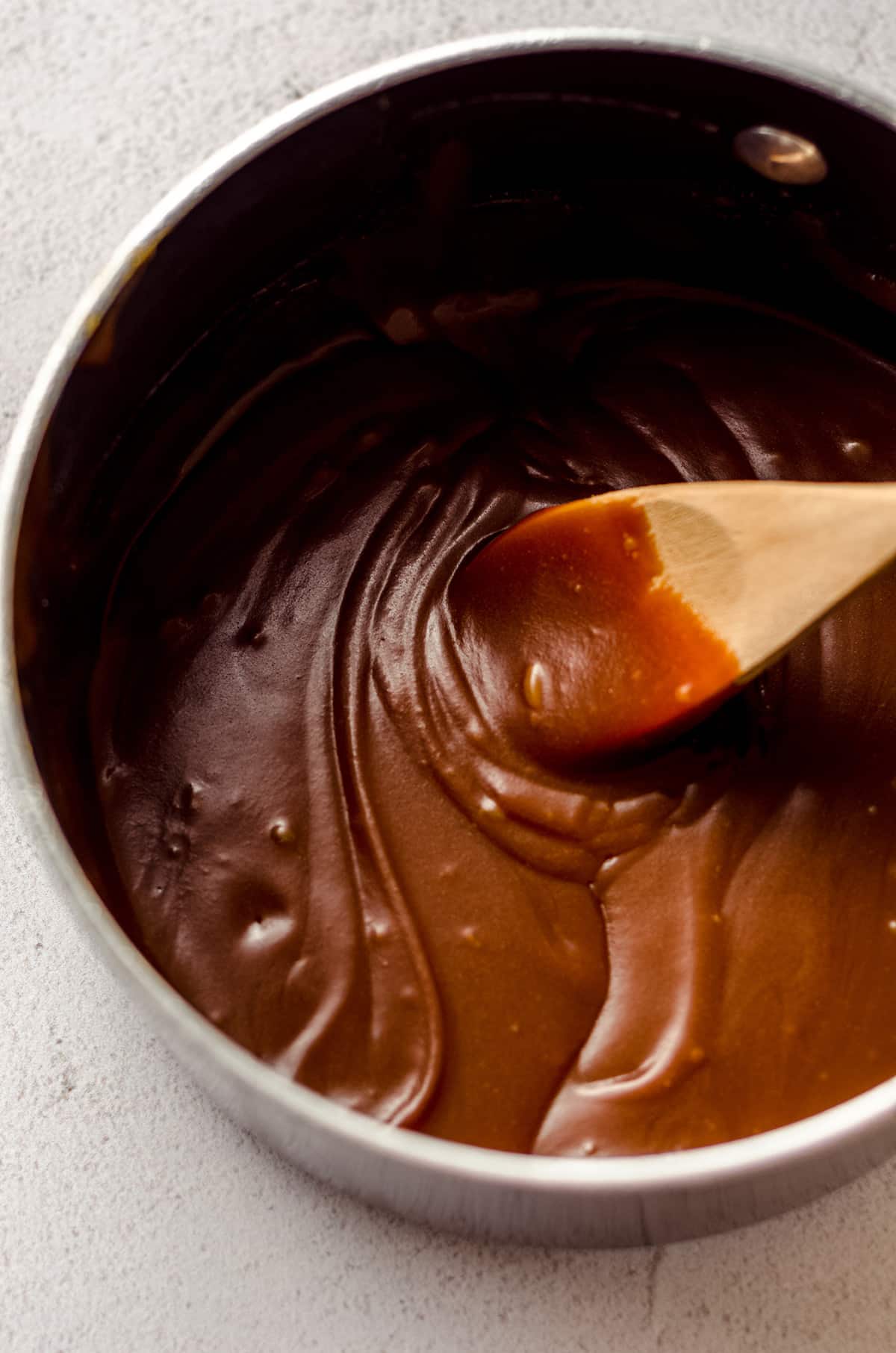wooden spoon stirring salted caramel sauce in a saucepan