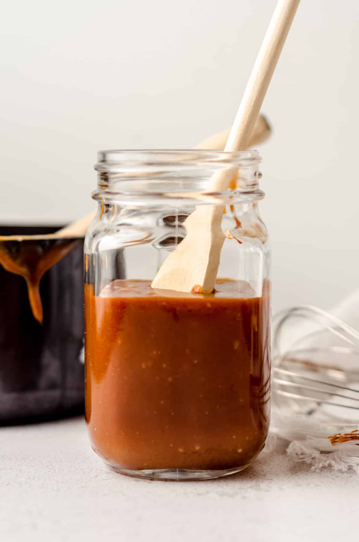 jar of salted caramel sauce with a wooden spoon sitting in it