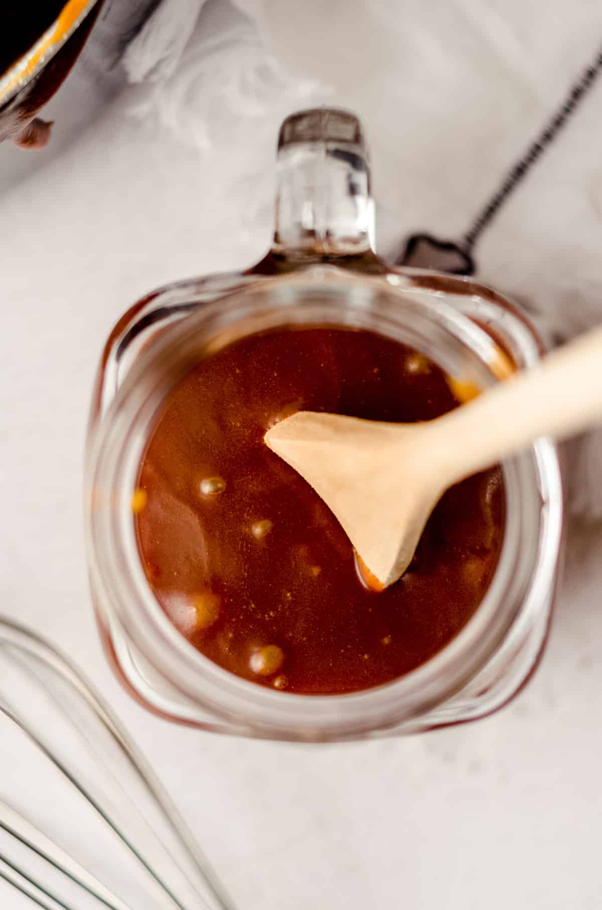 aerial photo of a jar of salted caramel sauce with a wooden spoon sitting in it