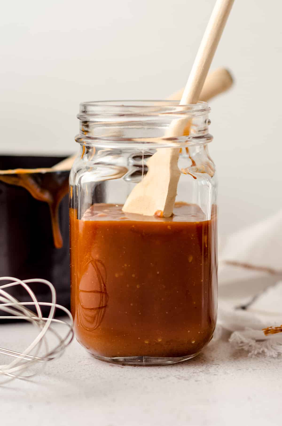 jar of salted caramel sauce with a wooden spoon sitting in it