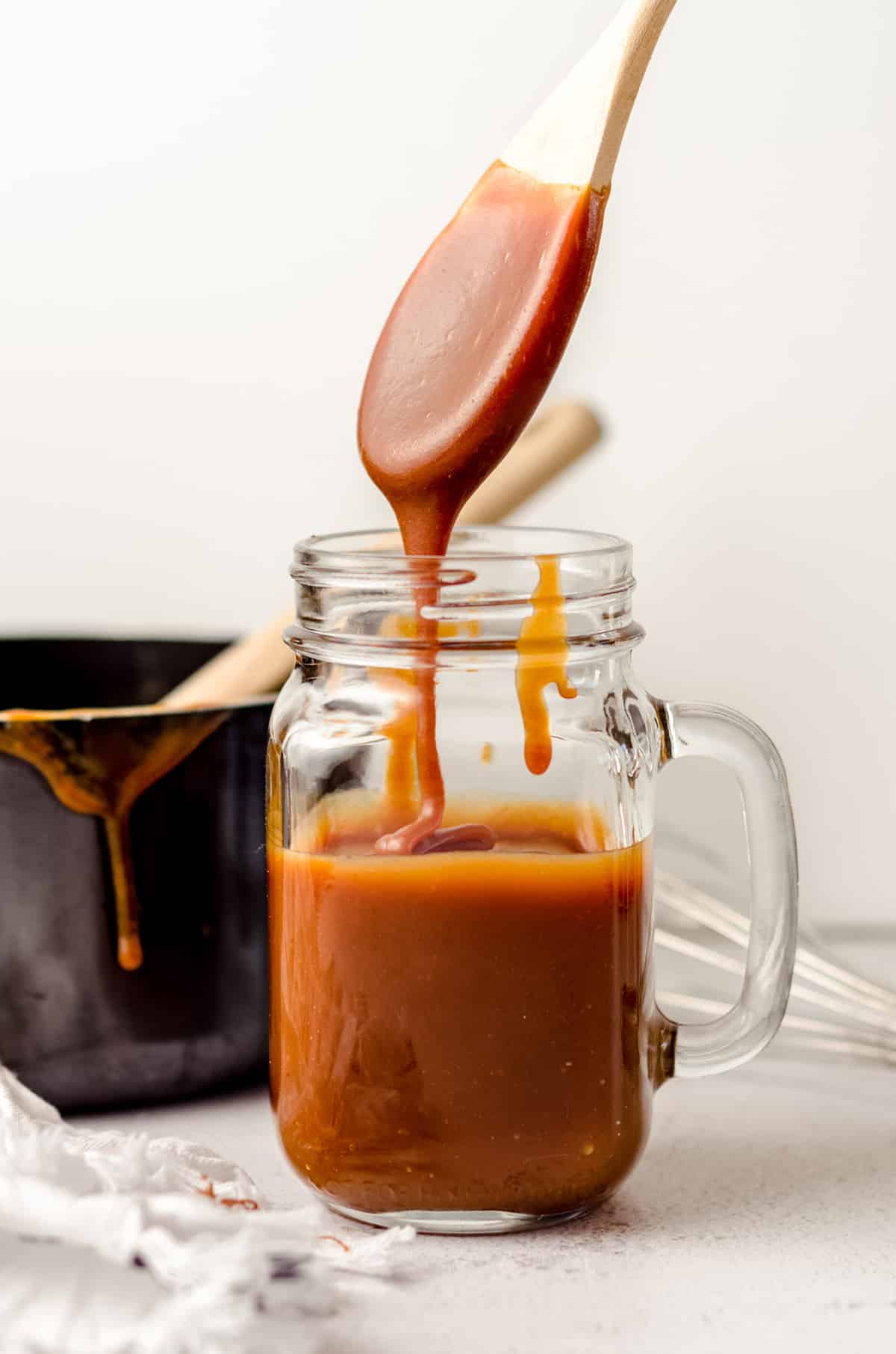 jar of salted caramel sauce with a spoon dipped into it dripping back into the jar
