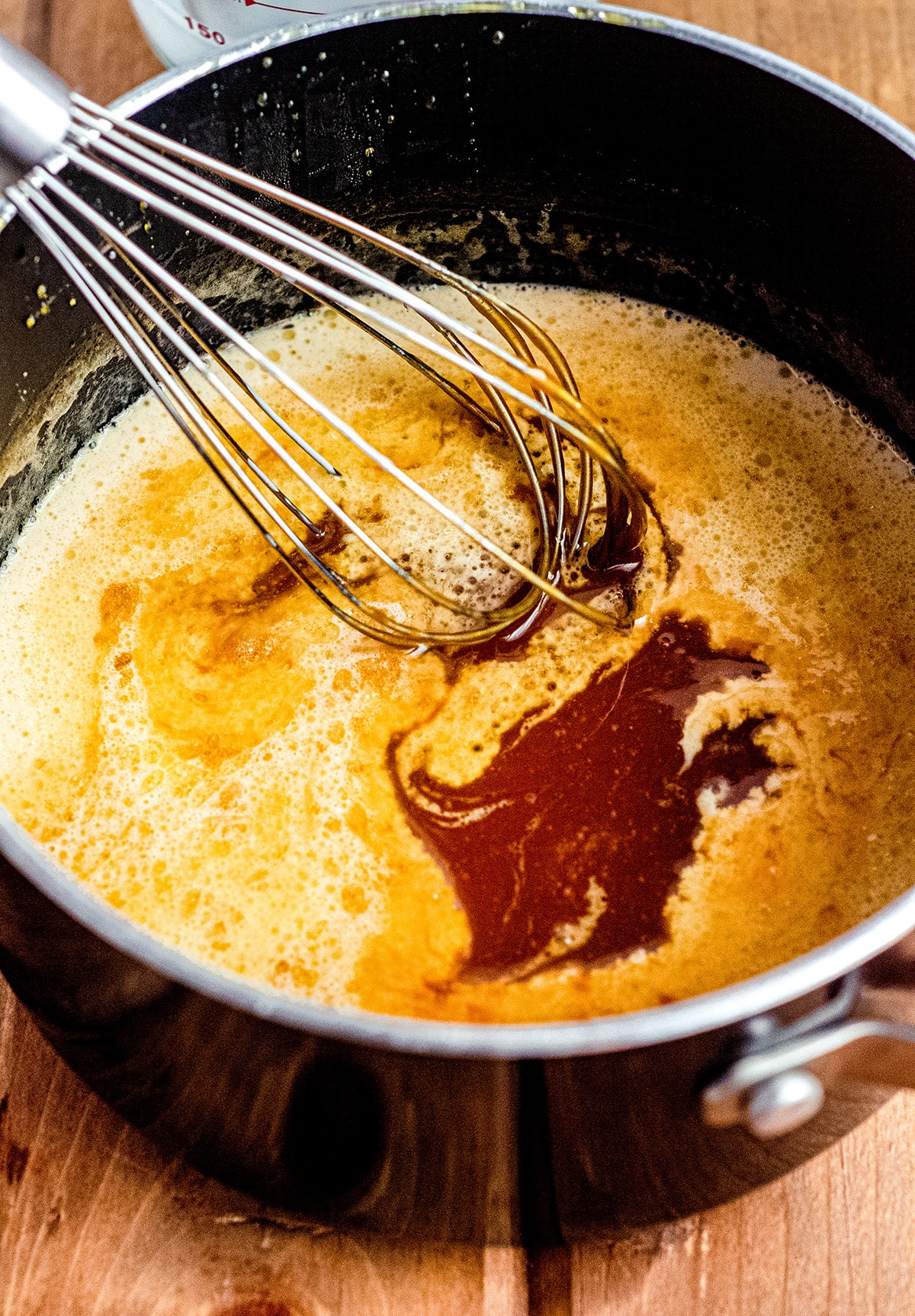 whisking heavy cream into homemade salted caramel sauce