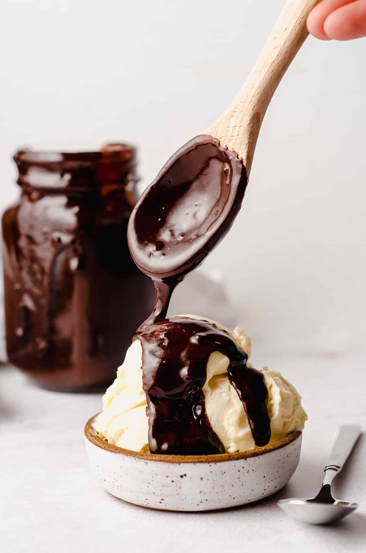 a spoon dripping homemade hot fudge sauce onto ice cream