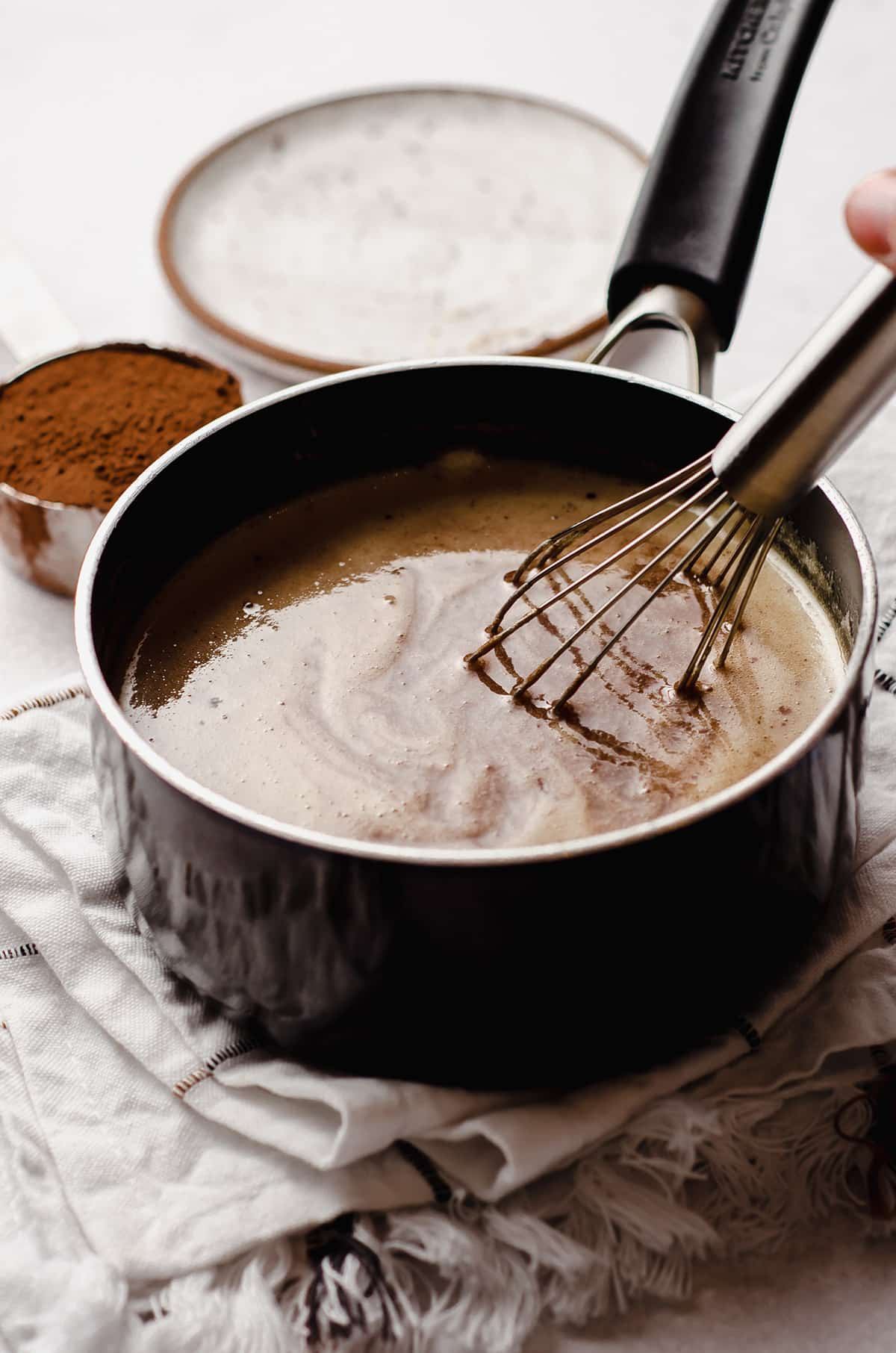 whisking ingredients together in a saucepan for homemade hot fudge sauce
