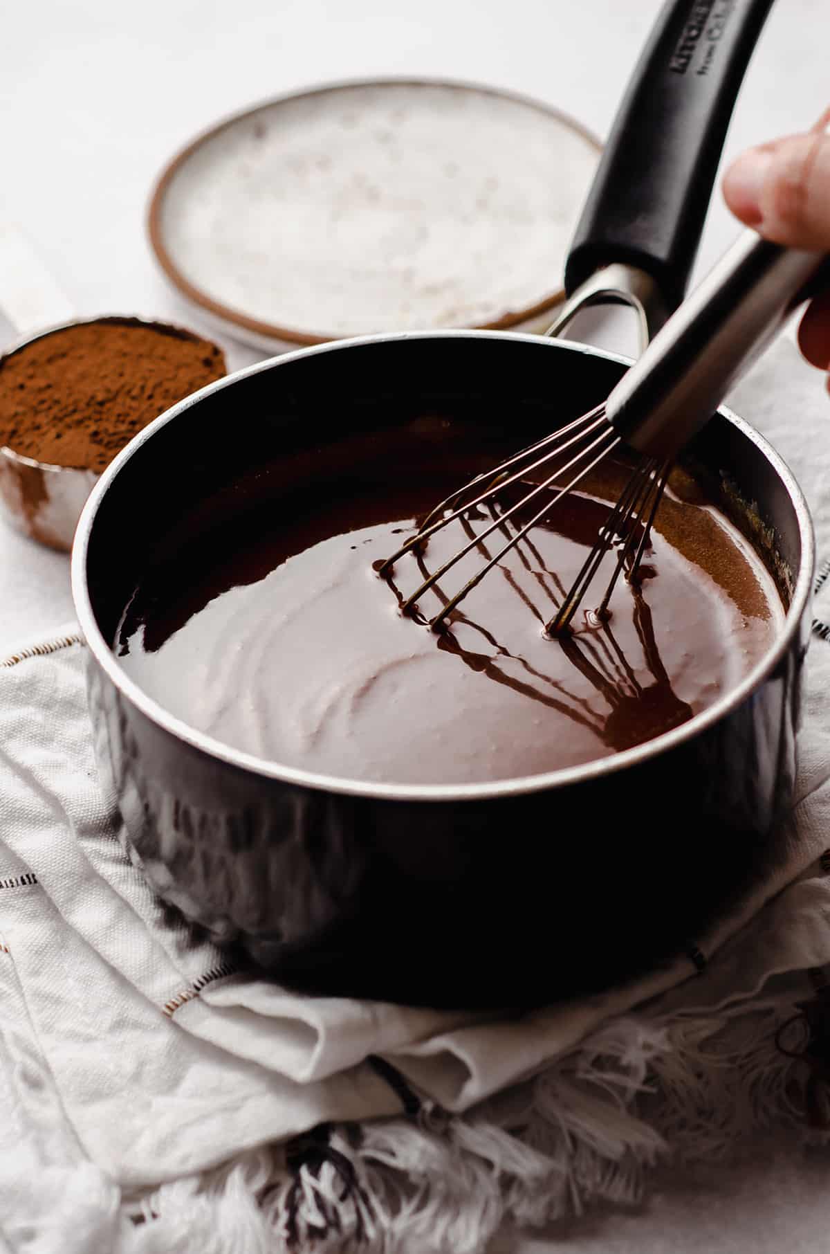 whisking ingredients together in a saucepan for homemade hot fudge sauce