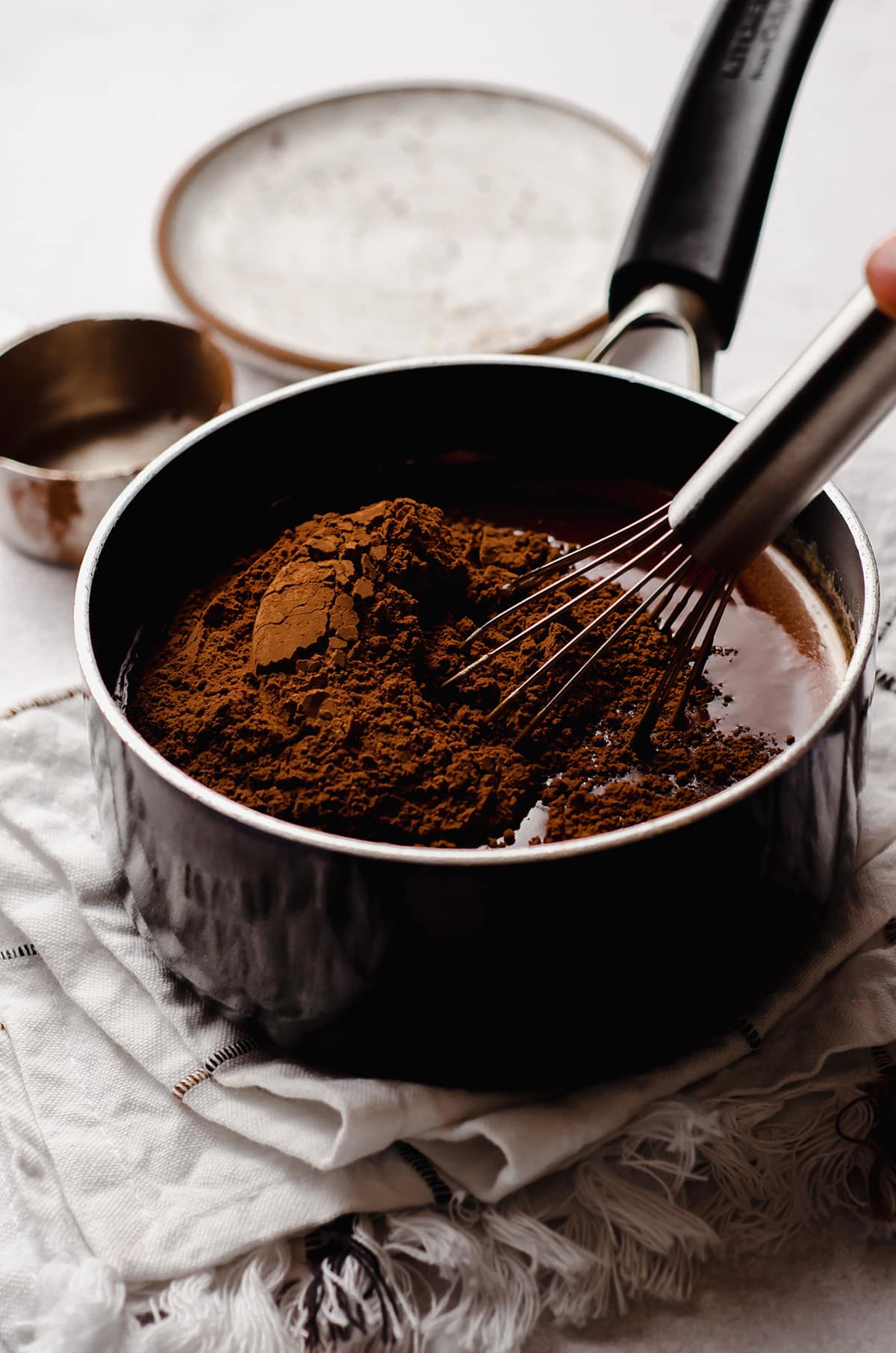 whisking ingredients together in a saucepan for homemade hot fudge sauce