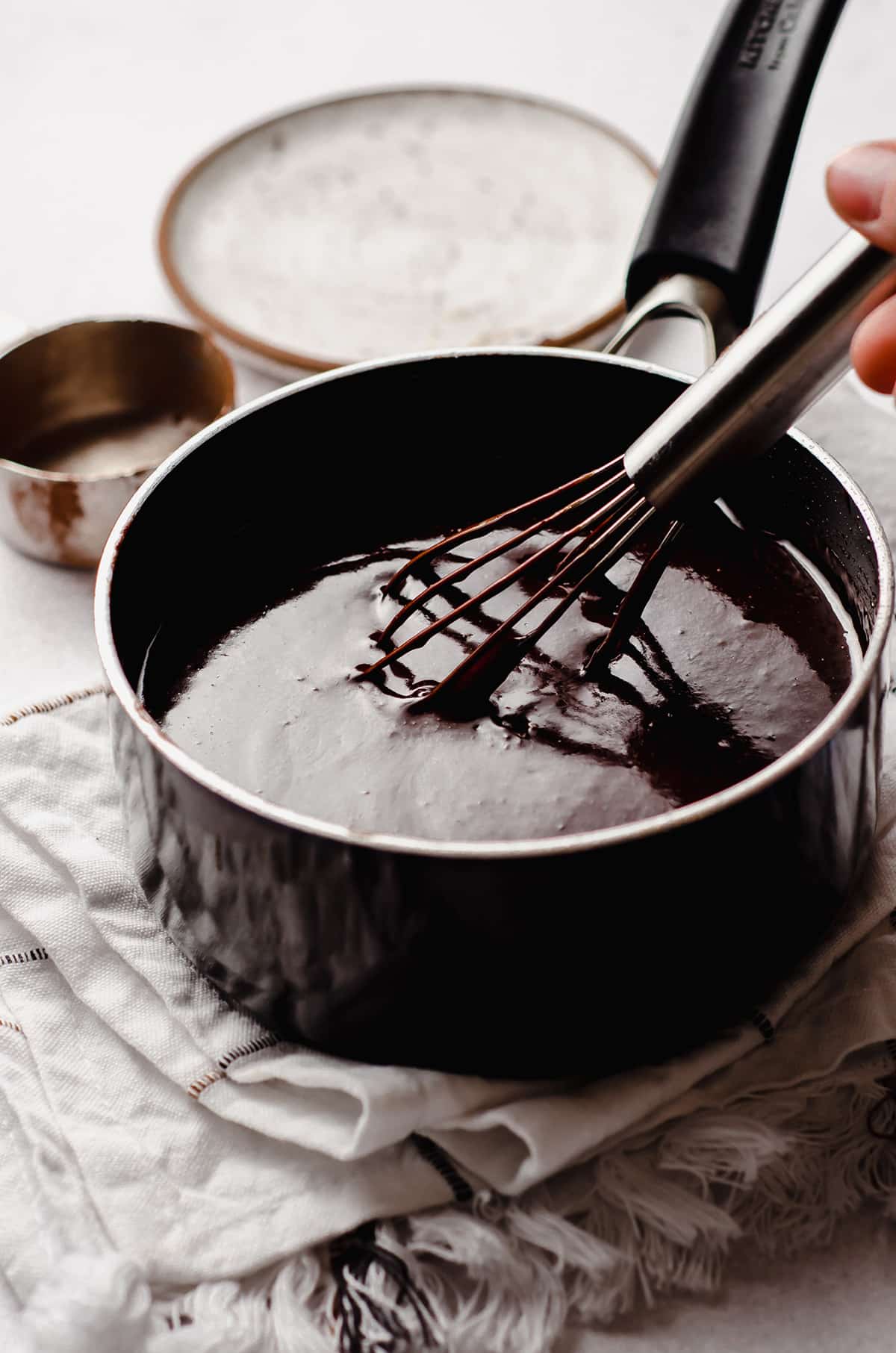 hot fudge sauce in a saucepan with a whisk