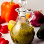 homemade italian dressing in a bottle with vegetables around it