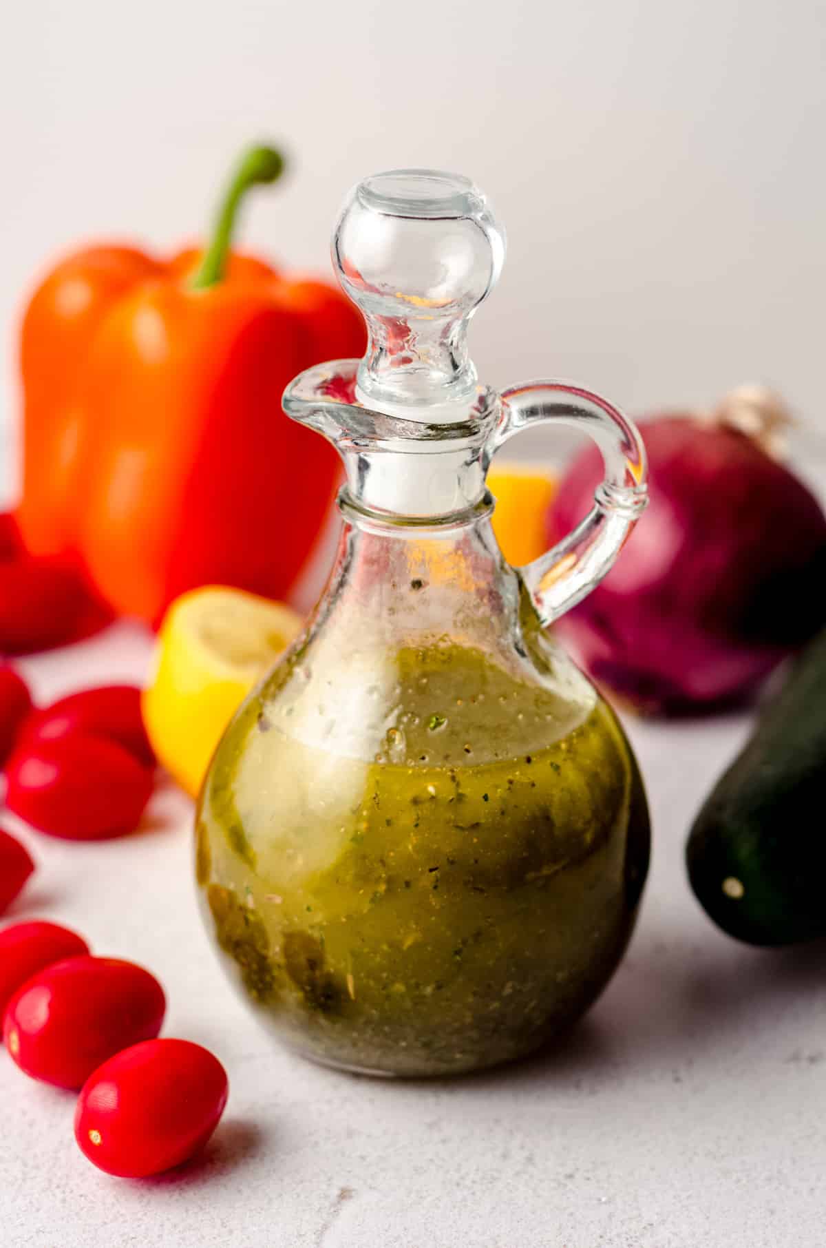 homemade italian dressing in a bottle with vegetables around it