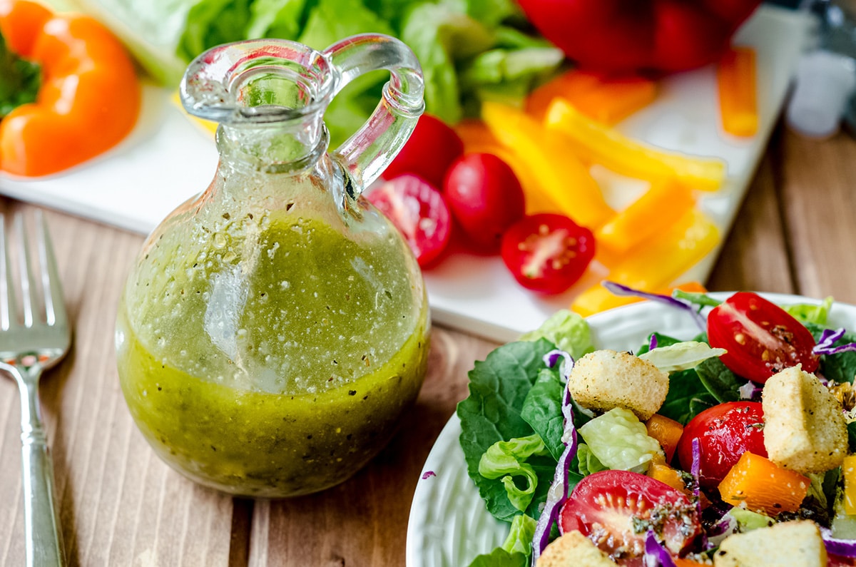 italian dressing in a bottle with salad in the background