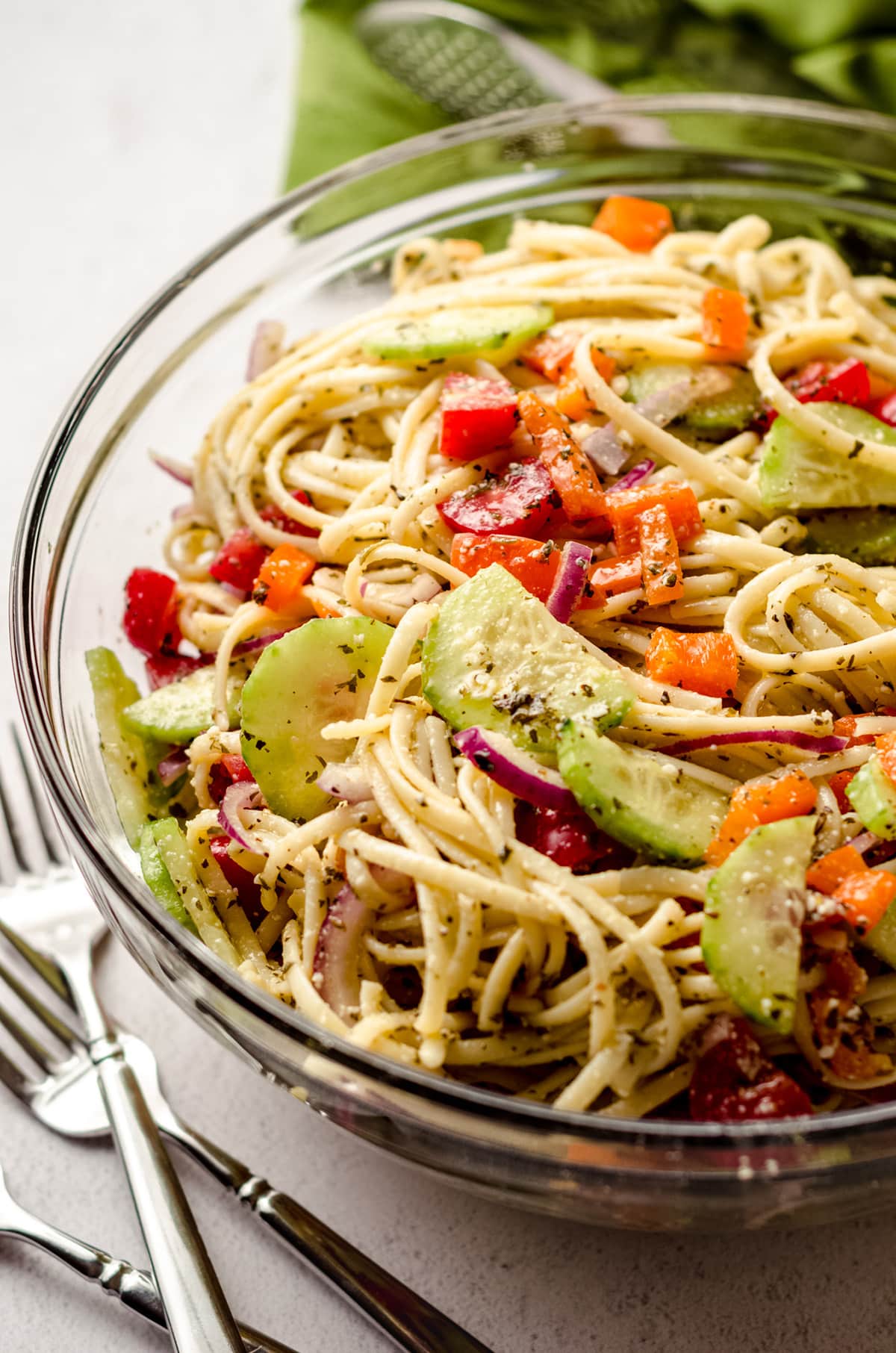 A close up of a serving bowl full of cold pasta salad with veggies.