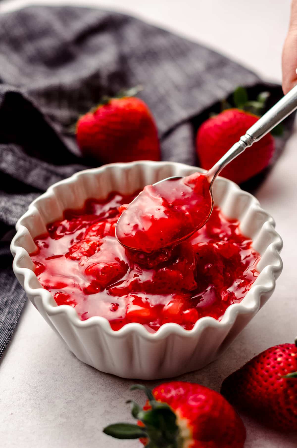 spoon lifting a scoop of easy strawberry compote out of a bowl