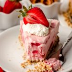 slice of strawberry pretzel pie on a plate with a fork and a bite taken out of it