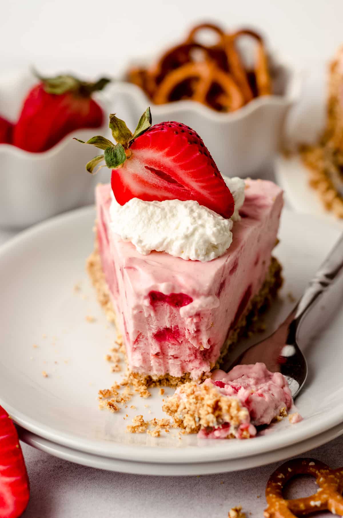 slice of strawberry pretzel pie on a plate with a fork and a bite taken out of it