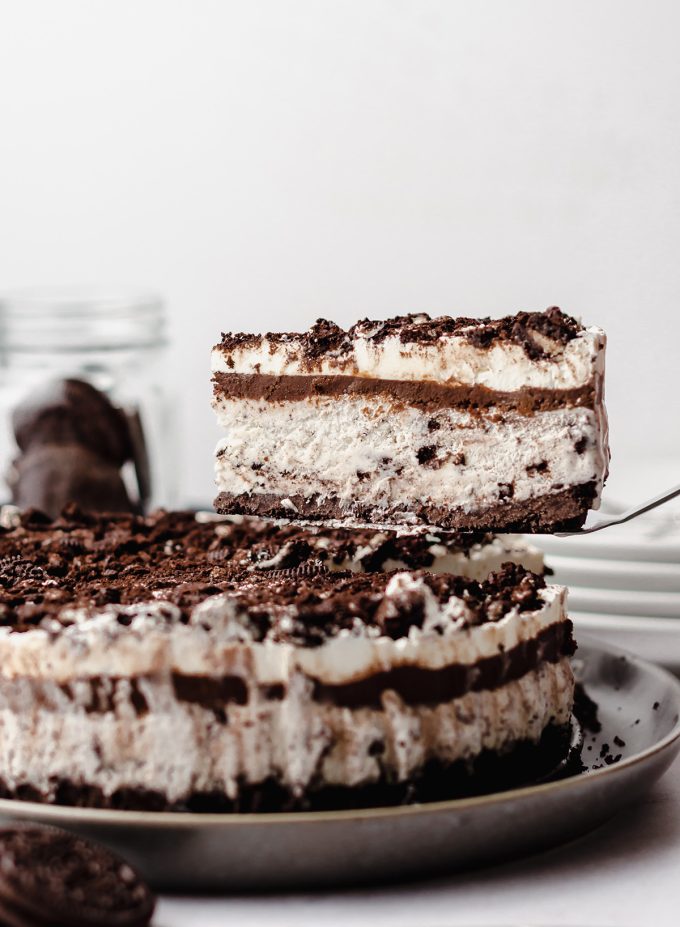 A cake lifter removing a piece of ice cream cake made with Oreo cookies.