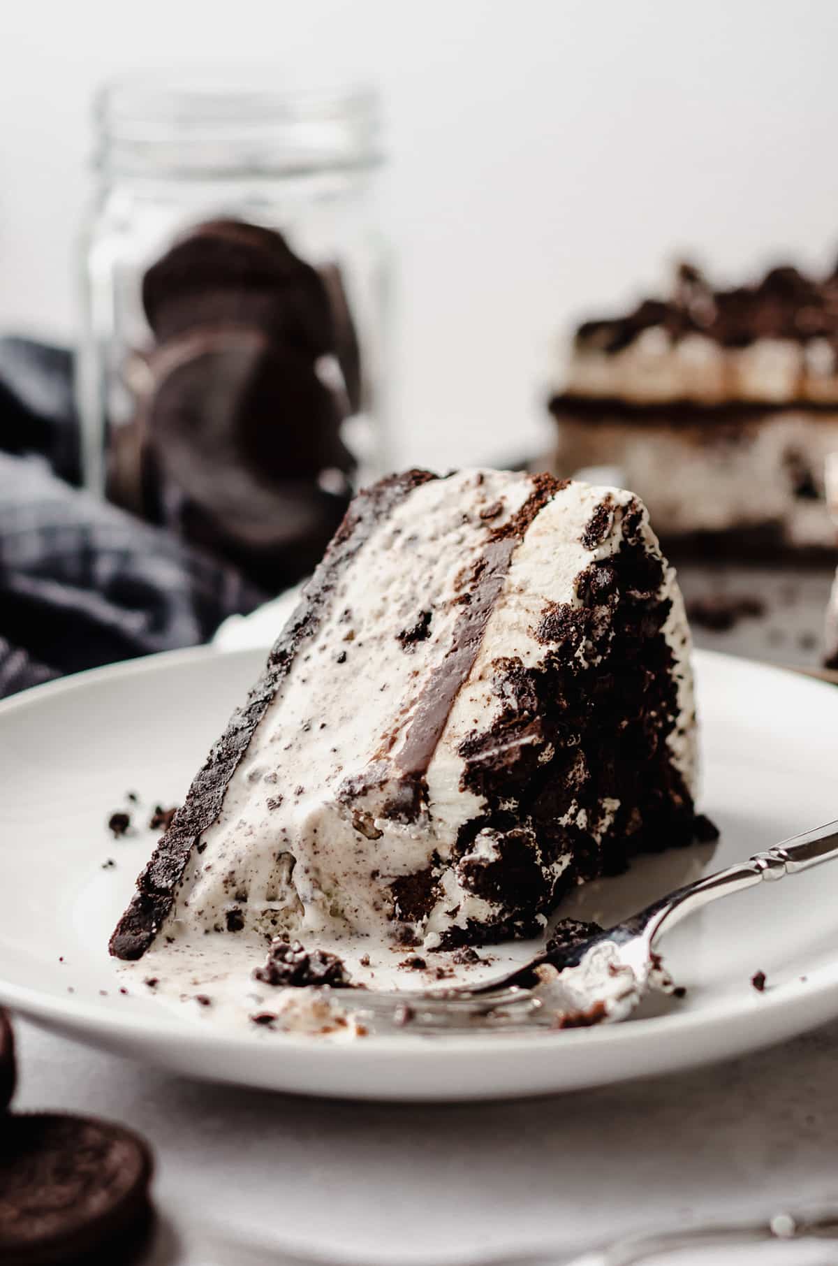A slice of cookies and cream ice cream cake on a white plate.