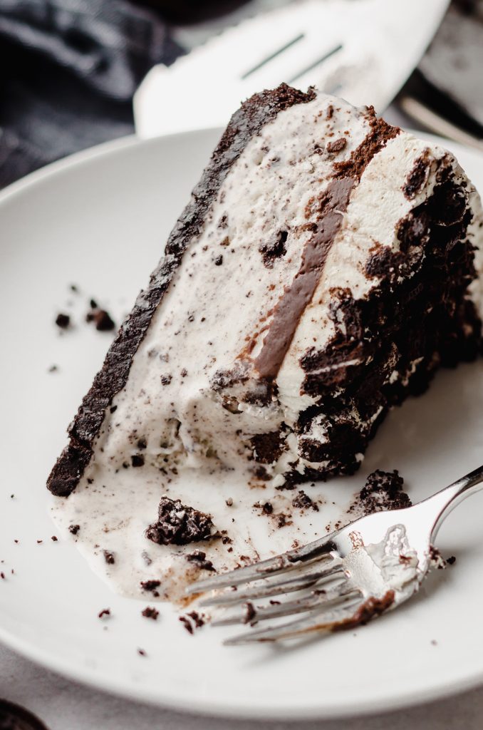 A slice of cookies and cream pie with a fork having removed a portion.