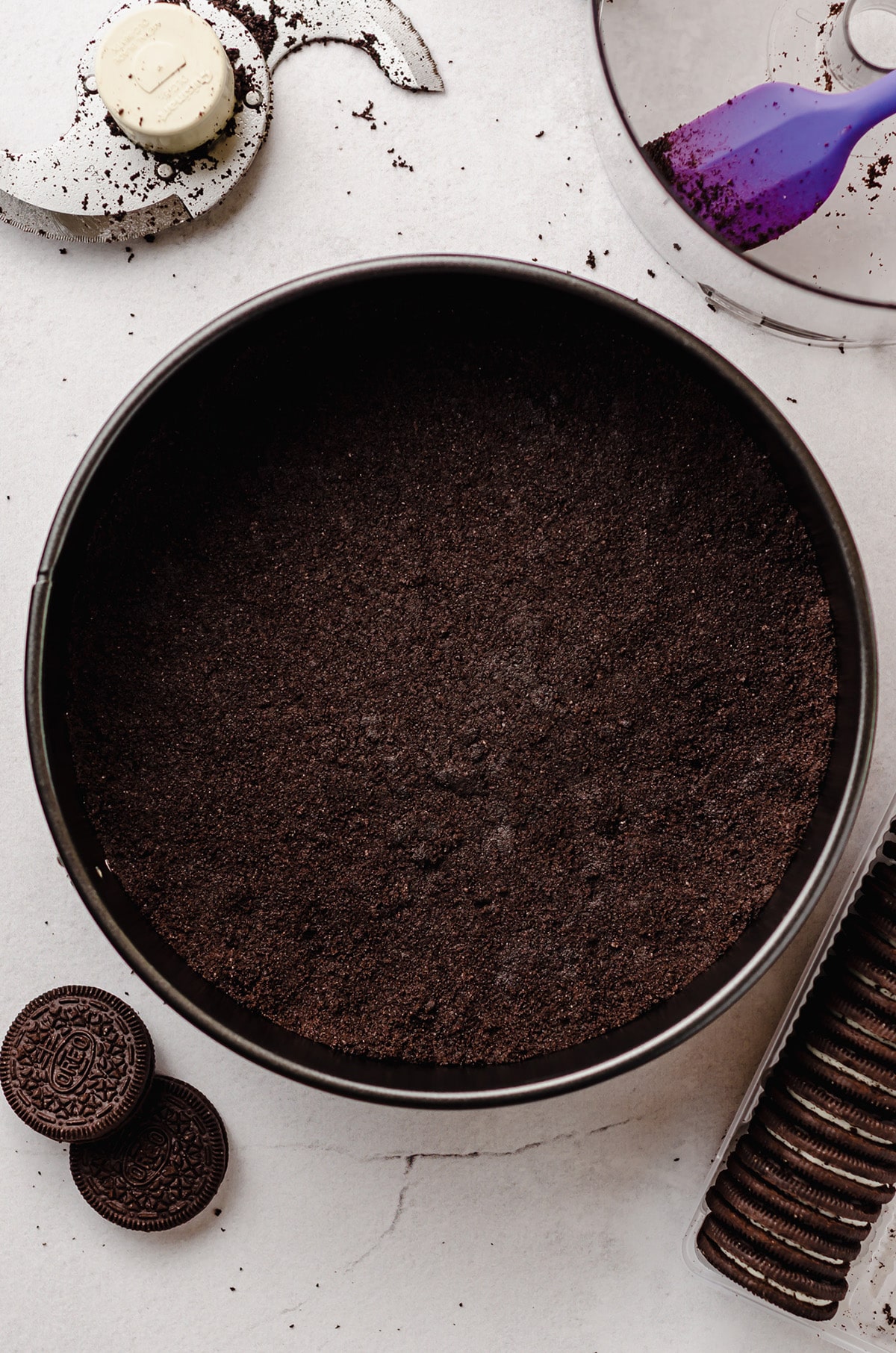 An Oreo crust inside of a springform pan on a white background.