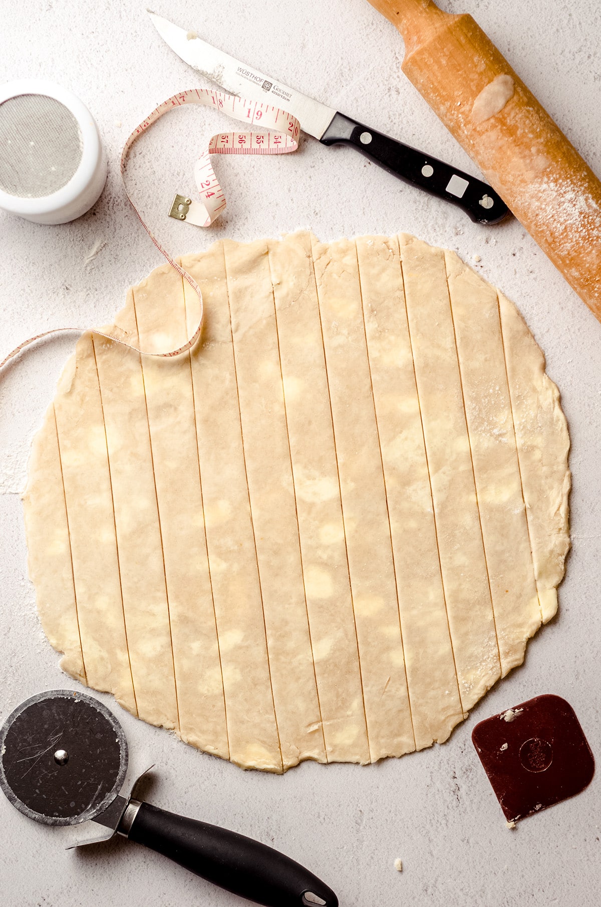 A circle of dough cut into pie dough strips.