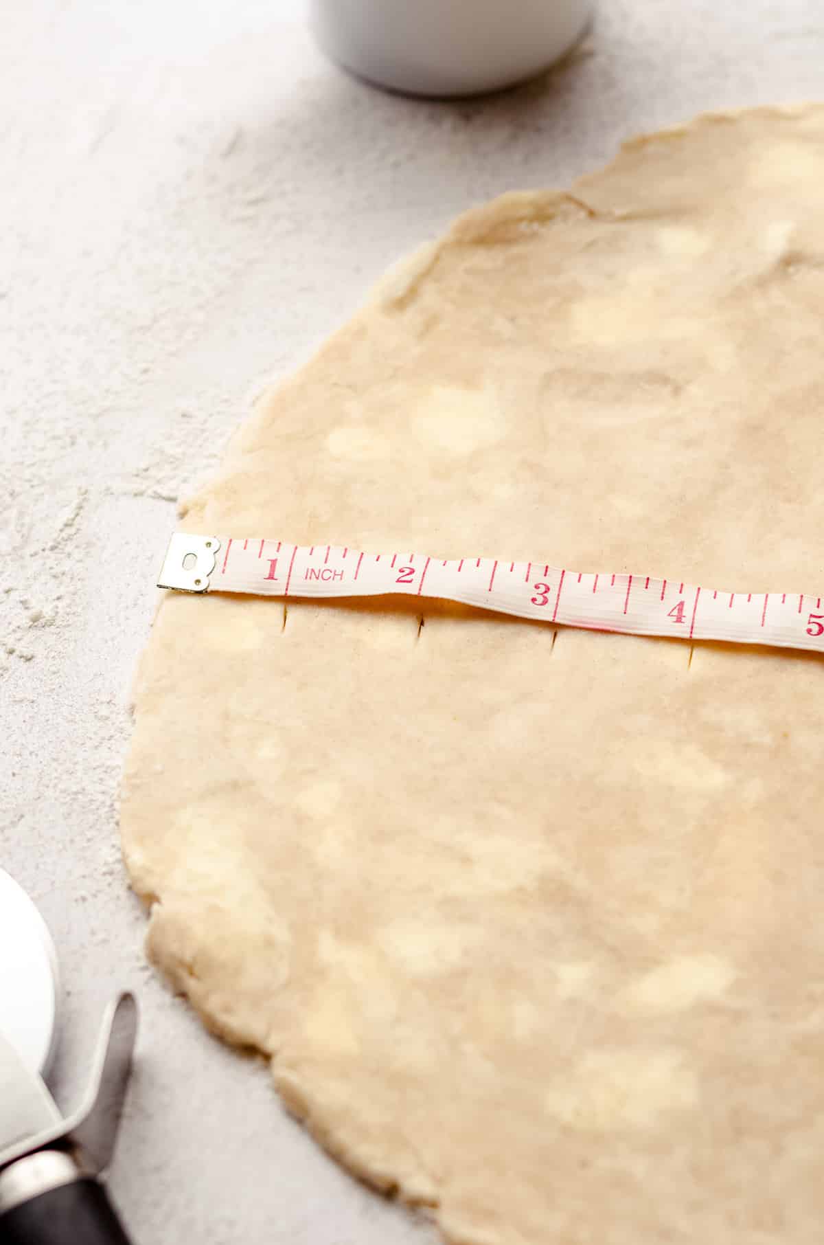 a tape measure on a disc of pie dough to cut lattice strips