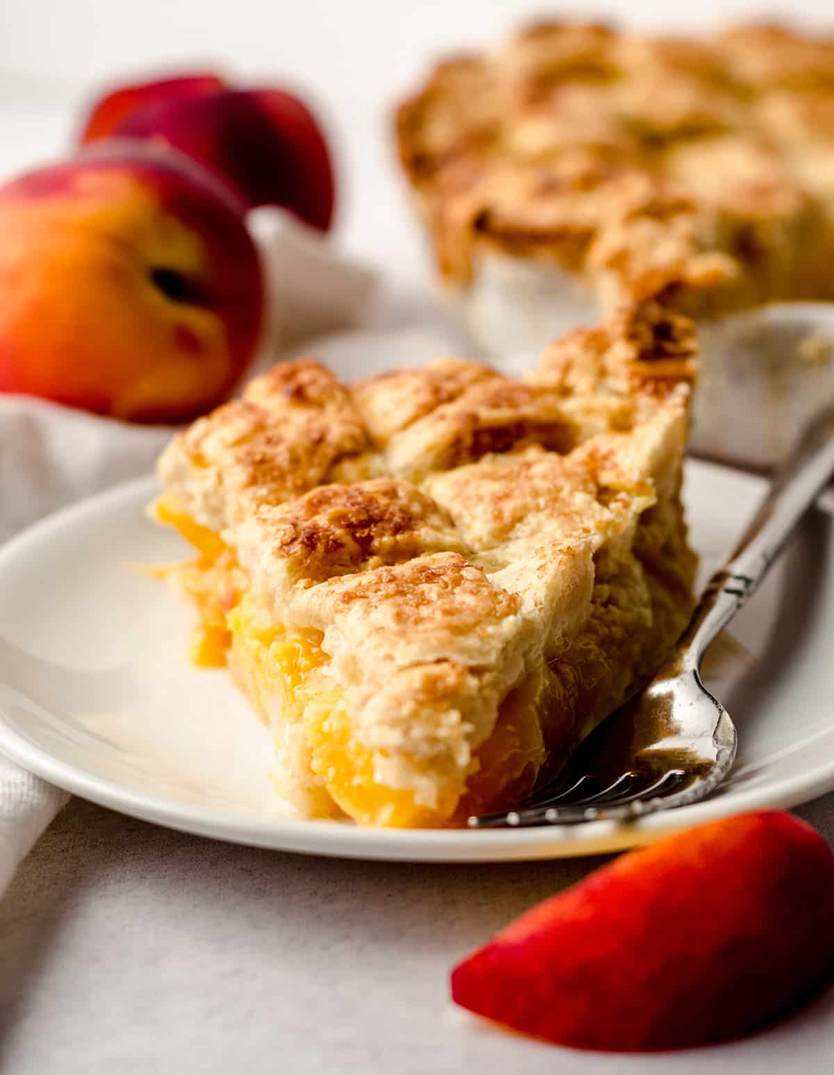 A slice of fresh peach pie with a lattice crust.