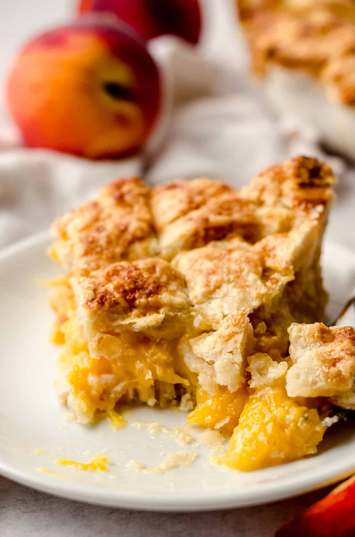A close up of a slice of peach pie with a portion taken out.