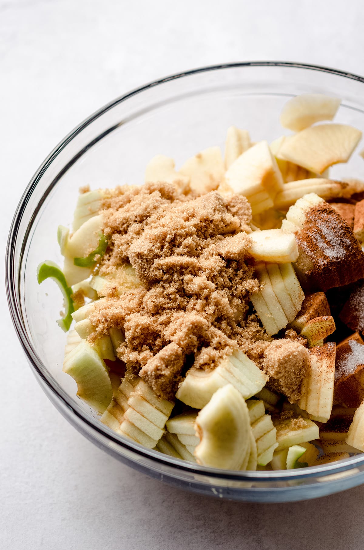 apple slices in a glass bowl coated in sugar and spices