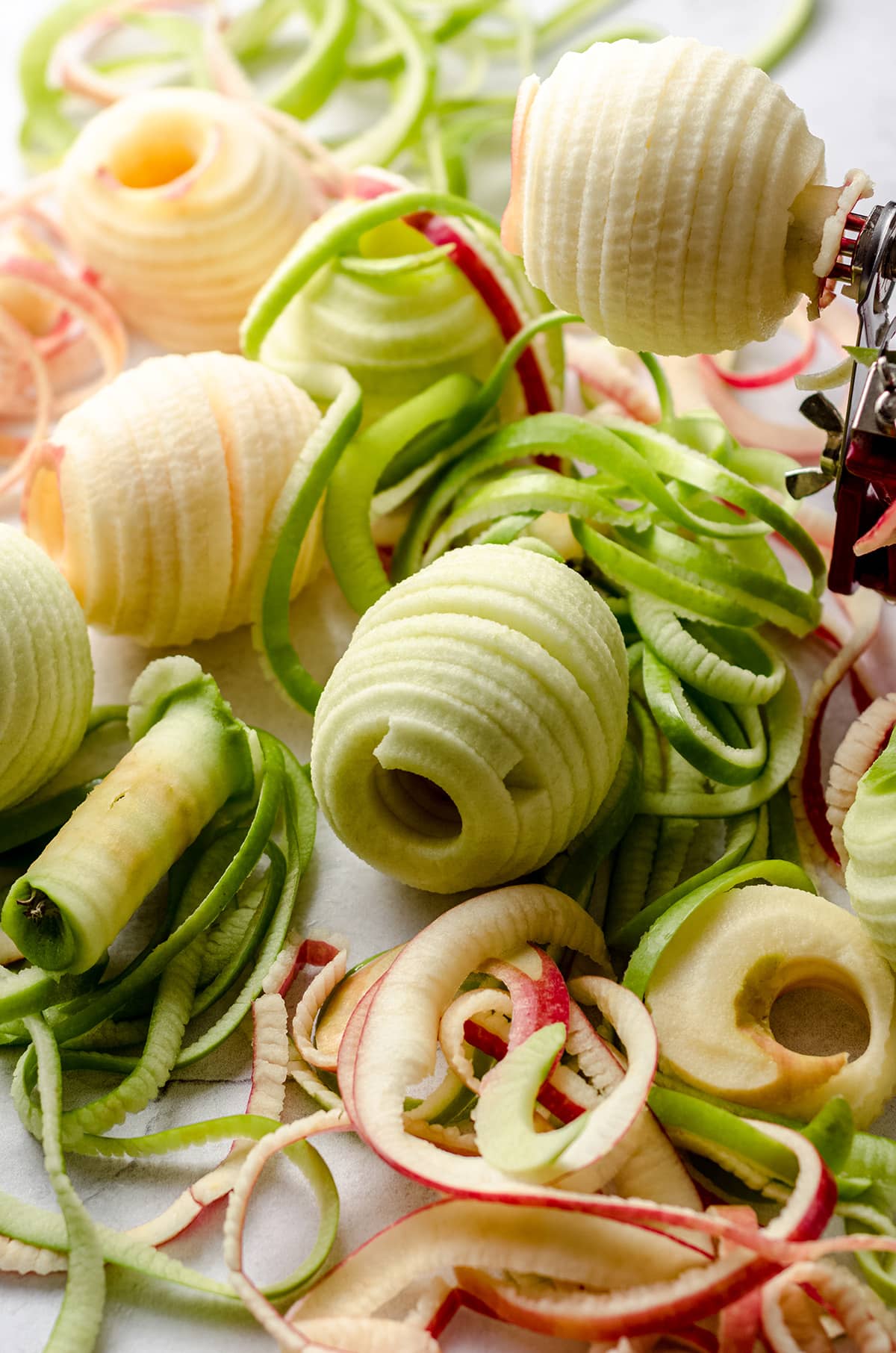 sliced and cored green and red apples with the skins sitting all around them