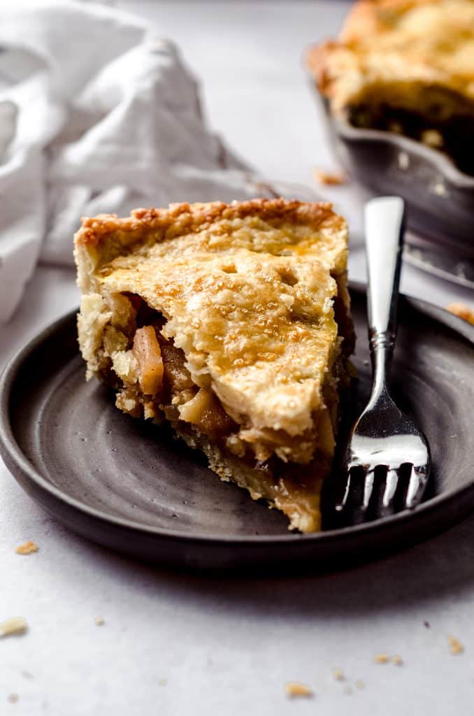 slice of homemade apple pie on a plate with a fork