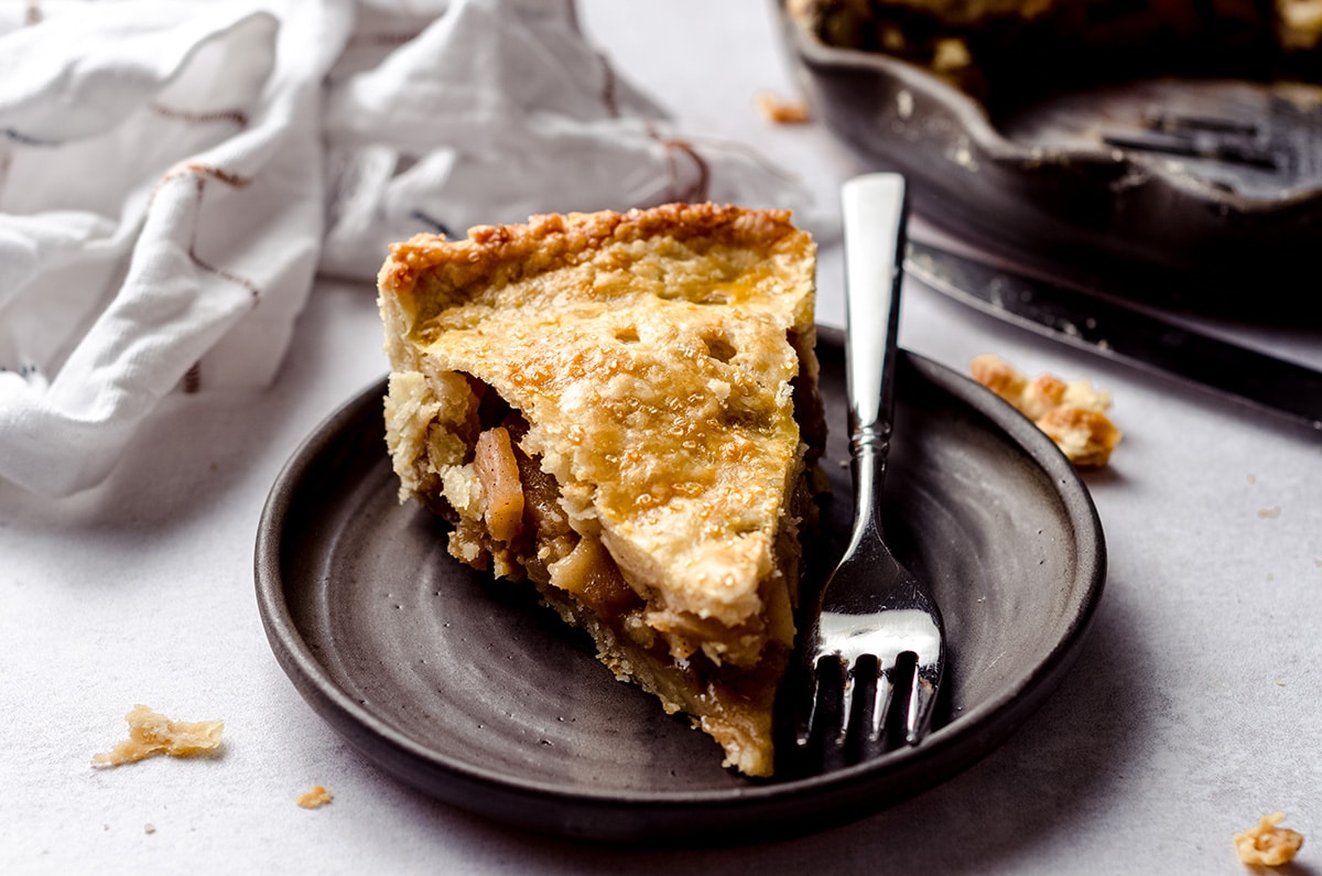 slice of homemade apple pie on a plate with a fork