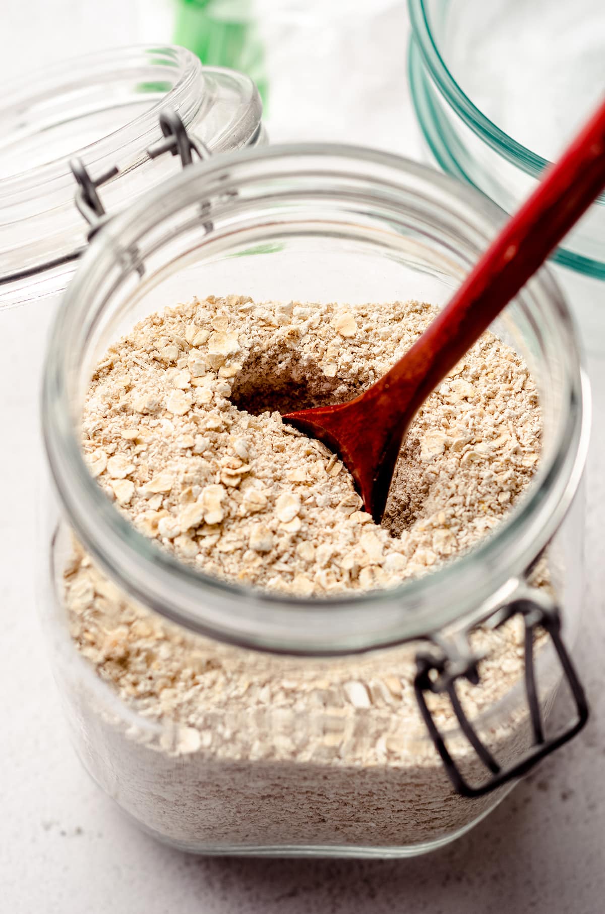 A large jar of oats with a wooden spoon in it.